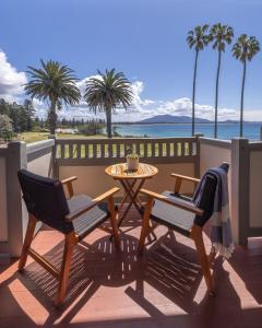 伯马吉Bermagui Beach Hotel的庭院设有两把椅子和一张桌子,并种植了棕榈树