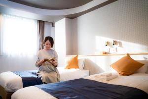 大阪Hotel S-Presso Central的坐在酒店房间两张床上的女人