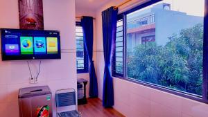 岘港Sena home 3#1-Near Danang Dragon Bridge-Han River的客房设有电视和带蓝色窗帘的窗户。