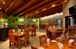白河eBundu Lodge的一间设有木桌和椅子的餐厅以及石墙