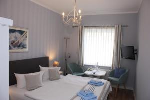 格赖夫斯瓦尔德Hotel Maria的一间卧室配有一张床、两把椅子和电视