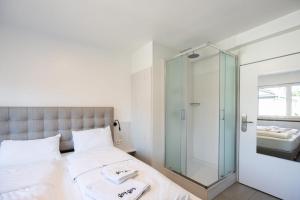 纽伦堡StayStay Guesthouse I 24 Hours Check-In的一间带玻璃淋浴间和一张床的卧室