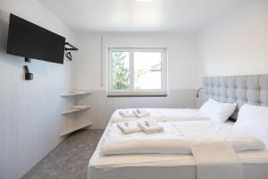 纽伦堡StayStay Guesthouse I 24 Hours Check-In的一间白色卧室,配有两张床和一台平面电视