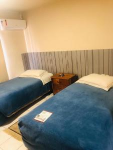 拉热斯Villa Apart Hotel的酒店客房设有两张床和床头柜。