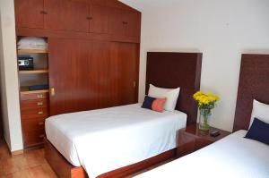 墨西哥城La Casita de Coyoacán的一间卧室设有两张床和木制橱柜