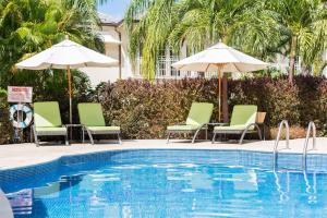 圣彼得教区Shimmers, stunning, stylish West Coast Villa的一个带椅子和遮阳伞的游泳池