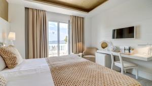 波连萨港Hotel Illa d'Or & Club Apts 4* Sup的配有一张床、一张书桌和一扇窗户的酒店客房