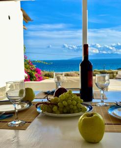 卡拉法蒂斯Thalia Myconian Suites的一张桌子,上面放着一盘葡萄和一瓶葡萄酒