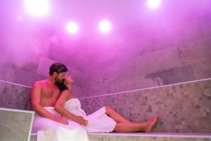 佩鲁贾Le Cappuccinelle Suites&SPA的男人和女人坐在紫色灯的浴缸里
