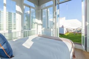 塞维利亚LS9- La Palmera Luxury by Valcambre的配有大窗户的客房内的一张床位