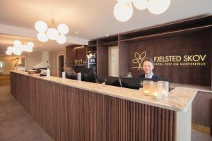 EjbyFjelsted Skov Hotel & Konference的坐在酒店大堂前台的人