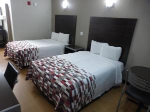 科珀斯克里斯蒂Red Roof Inn Corpus Christi North - Near Downtown的酒店客房设有两张床和一张桌子。