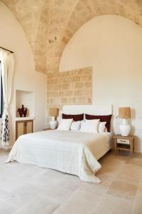 萨维勒特里Masseria Calderisi的卧室配有一张白色大床和石质天花板