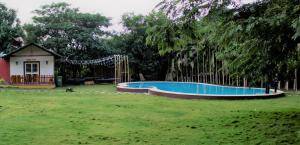 浦那Aranyagiri Countryside Resort, Near Pune的一座房子旁的院子内的游泳池