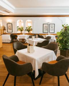 路茨曼贝格四季酒店的一间设有白色桌椅的餐厅,种植了植物