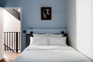 巴黎Edgar Suites Notre-Dame - Lagrange的卧室配有白色的床和蓝色的墙壁