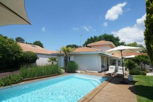 安德诺莱斯贝恩Chambres d'hôtes Villa Surcouf的一座带遮阳伞的房屋前的游泳池
