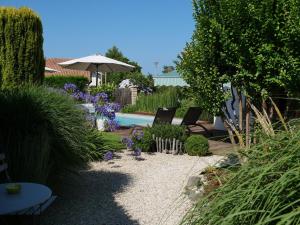 安德诺莱斯贝恩Chambres d'hôtes Villa Surcouf的花园配有两把椅子和一把遮阳伞