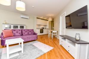 斯文托伊Irklo apartamentai su vaizdu į jūrą的客厅配有紫色沙发和桌子