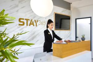 海若克利欧Stay 365 Heraklion Apart Hotel的站在桌子前的女装