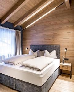 朗根费尔德Alpenchalet Tirol的一间卧室设有一张带木墙的大床