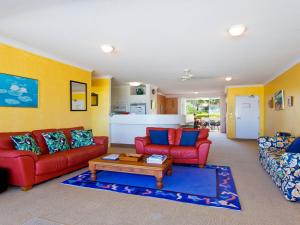 阳光海岸Cote DAzur 6 Douglas Street 6的客厅配有2张红色沙发和1张咖啡桌