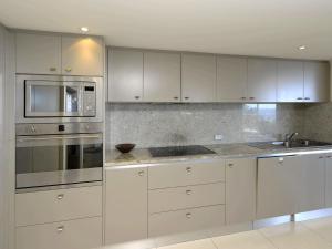 尼尔森湾Oasis Unit 9 5 Laman Street的厨房配有白色橱柜和不锈钢用具