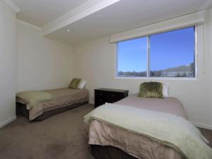 尼尔森湾Oasis Unit 9 5 Laman Street的一间卧室设有两张床和大窗户