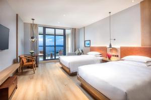 淳安voco千岛湖阳光大酒店的酒店客房设有两张床、一张桌子和一台电视。