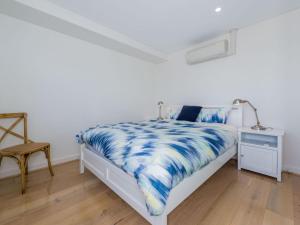 浅滩湾The Shoal Unit 405 Shoal Bay的一间卧室配有一张带蓝色和白色棉被的床
