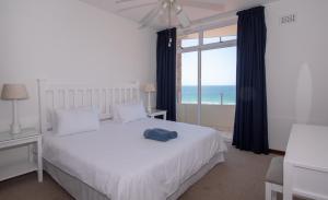 德班45 Sea Lodge Umhlanga Rocks的卧室设有白色的床和大窗户