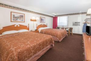 拉勒米Super 8 by Wyndham Laramie的酒店客房设有两张床和一张桌子。