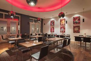 贝尔法斯特Ramada by Wyndham Belfast的餐厅设有桌椅和粉红色的天花板
