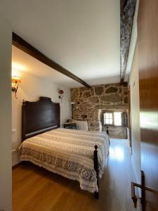 皮同伊斯-达斯-朱尼亚斯卡萨坎普费雷拉度假屋的一间卧室设有一张带石墙的大床