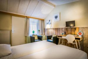 HulsbergCarré Hotel Zuid-Limburg的酒店客房,配有一张床、一张桌子和椅子