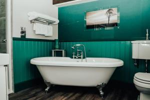 迪韦齐斯The Peppermill Town house Hotel & Restaurant的绿色浴室设有浴缸和卫生间