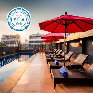 曼谷Hotel Solo, Sukhumvit 2, Bangkok - SHA Extra Plus的屋顶游泳池的一排椅子和遮阳伞