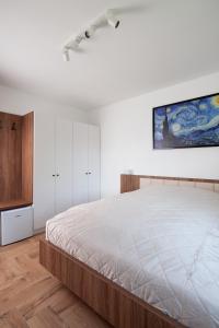 迈泽克韦什德HVT Comfort Apartments的卧室配有一张大床,墙上挂有绘画作品