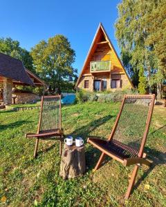 LežimirRustic cottage JARILO, an oasis of peace in nature的两把椅子坐在小屋前的立柱上