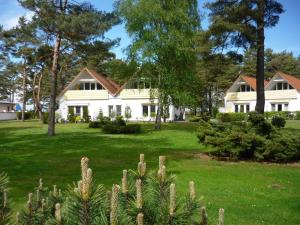 普雷罗Ferienanlage "Haus hinter den Dünen" Prerow的白色的房子,有树木和绿色的草地
