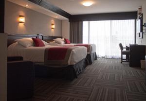 莱昂Ramada Plaza by Wyndham Leon的酒店客房设有两张床和窗户。