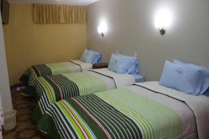 卡哈马卡Hotel Alpamayo Cajamarca的酒店客房,配有3张带蓝色枕头的床