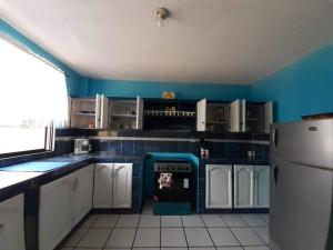 洛哈Amplio y cómodo departamento.的厨房设有蓝色的墙壁、白色的橱柜和冰箱。