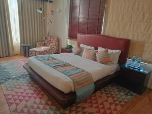瑞诗凯诗Hotel Natraj Rishikesh的一间卧室配有一张大床和一把椅子