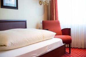 杜塞尔多夫豪斯艾美珠酒店的一间卧室配有一张床和一张红色椅子