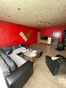 卢科维特Vilhelmov’s apartament的客厅设有红色的墙壁和黑色皮革家具