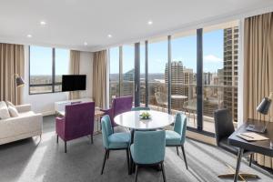 悉尼Meriton Suites Pitt Street, Sydney的酒店客房设有桌椅和大窗户。