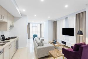 悉尼Meriton Suites Pitt Street, Sydney的厨房以及带紫色椅子和电视的客厅。