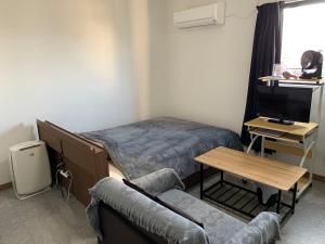 Hukueコンドミニアムホテル　Stay inn Blue room302的客厅配有床、沙发和电视。