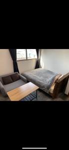 Hukueコンドミニアムホテル Stay inn Blue的一间卧室配有一张床、一张沙发和一个窗口